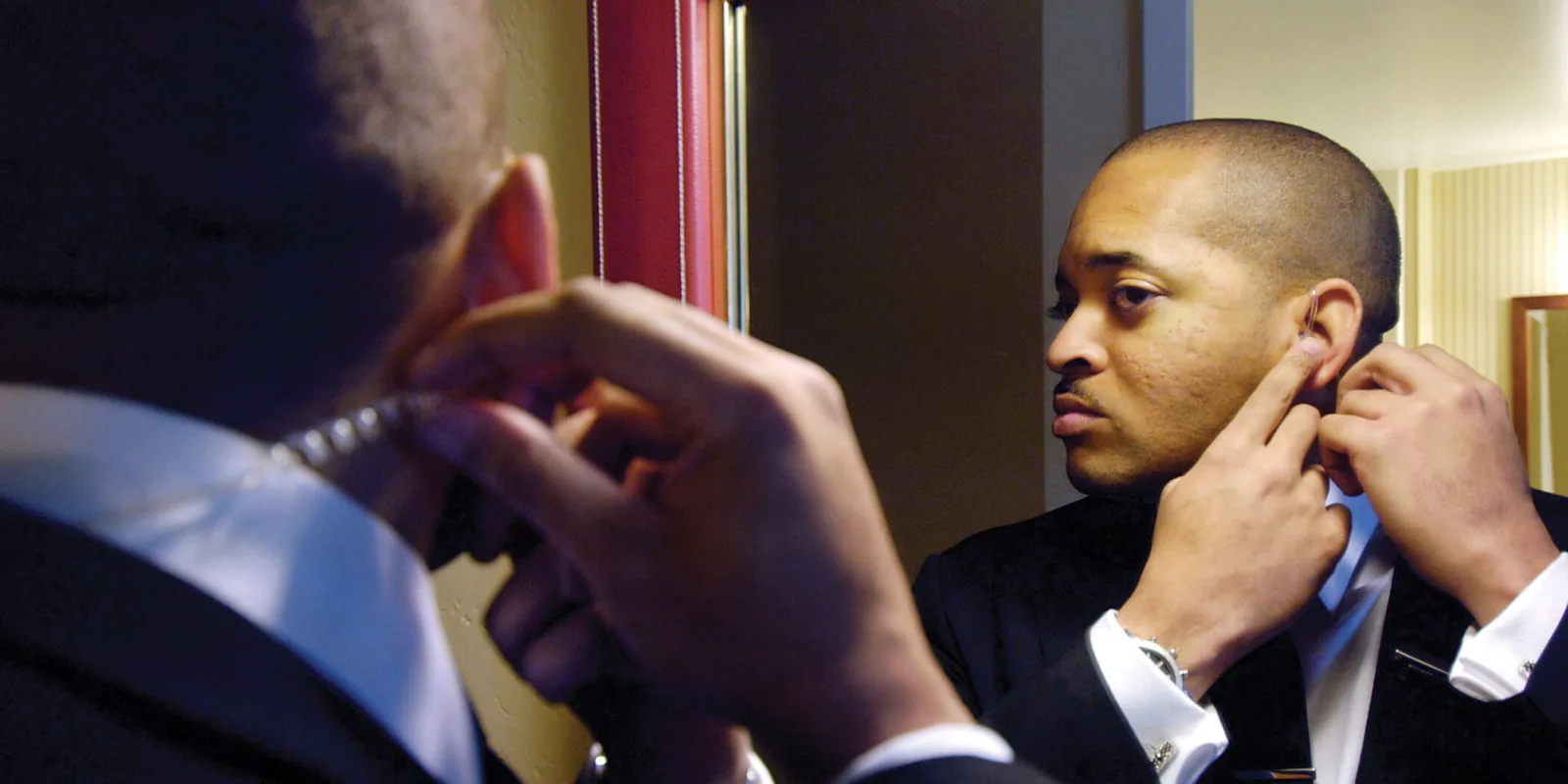 Protection agent fitting his earpiece in a mirror