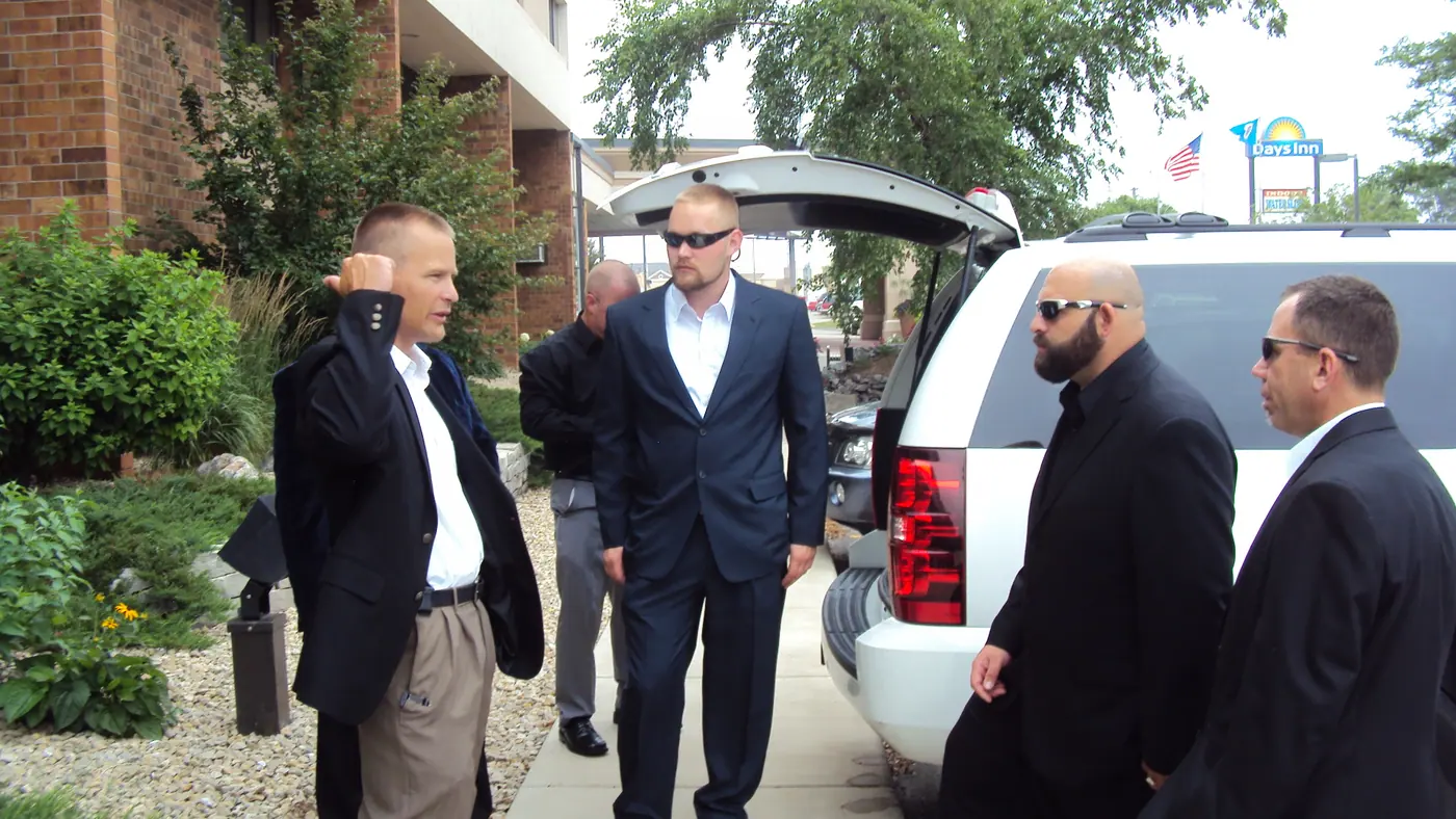 Protection team briefing beside an SUV before a movement